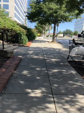 A picture of the sidewalk looking left from the station elevator. The street is on the right and the picture shows a slight incline to the intersection of 7th Street and Maryland Avenue.